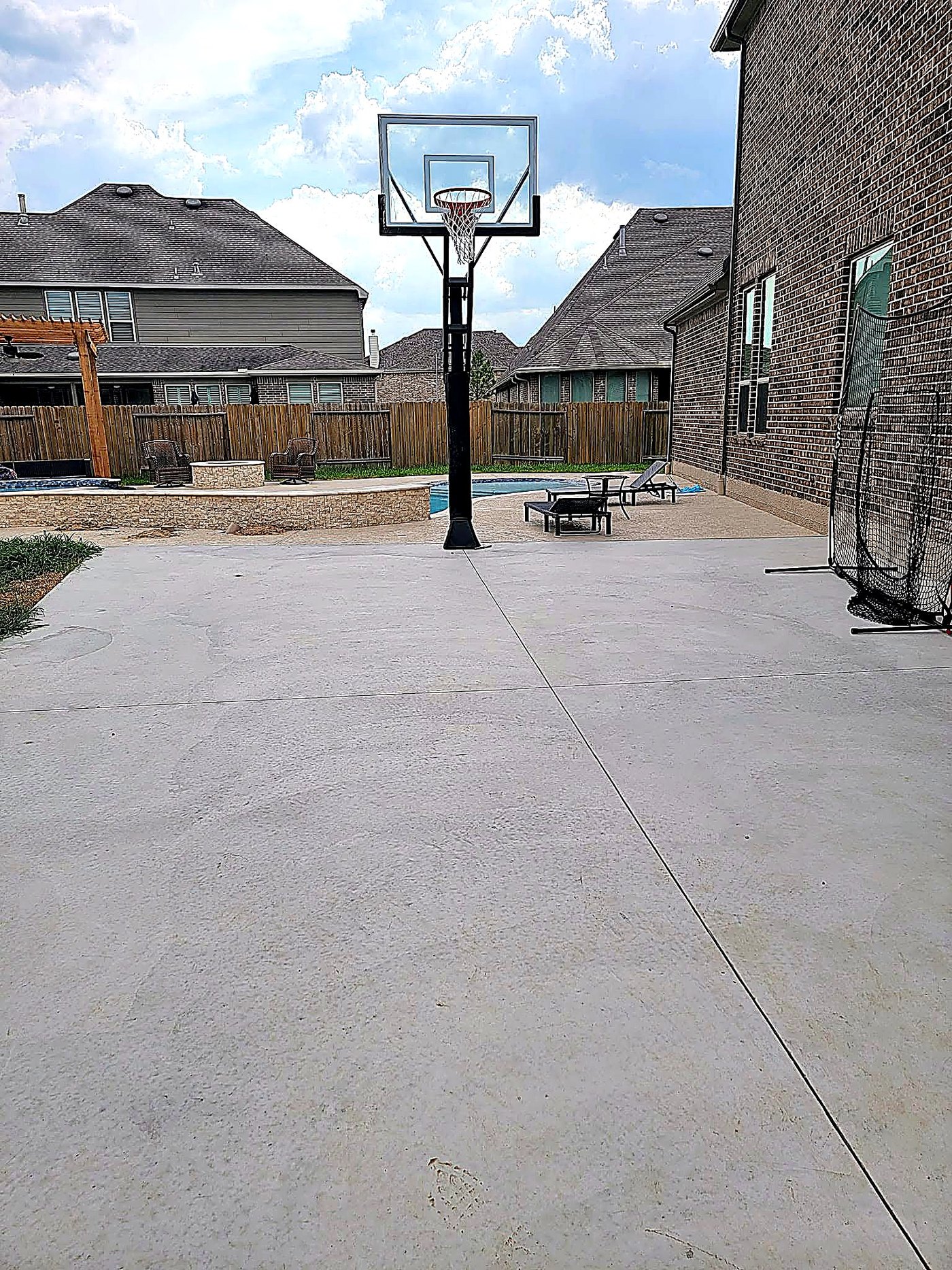 Backyard basketball court poured beside a custom pool and fire pit
