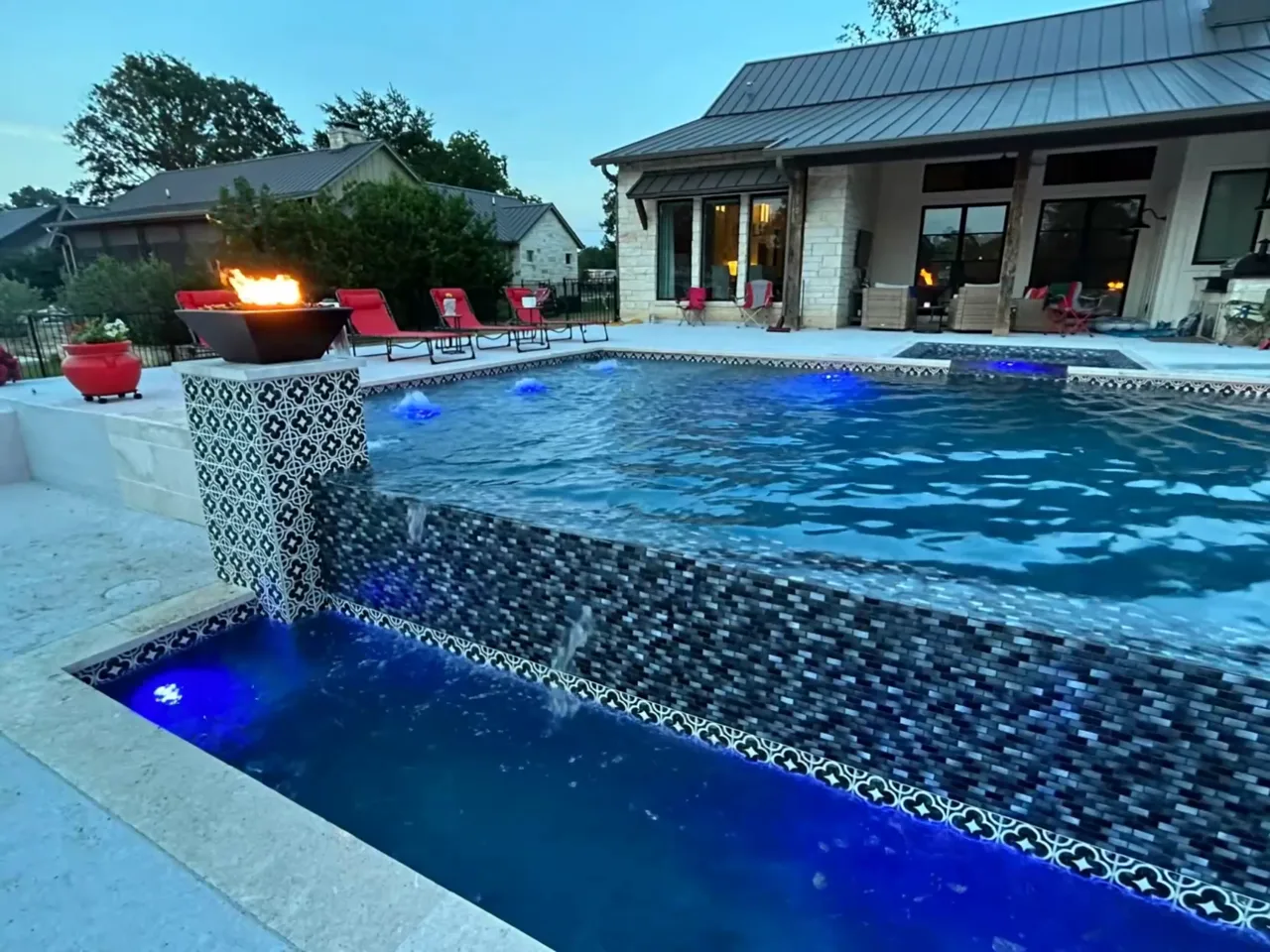 Fire bowl and sheer-descent spillway on a custom gunite pool at dusk